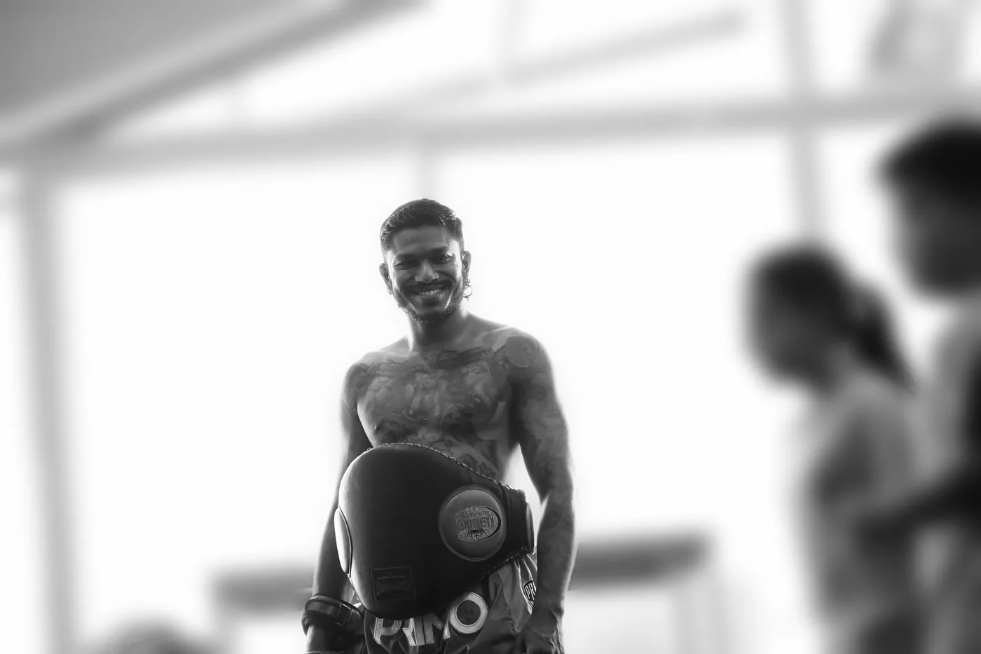 Sham smiling with a belly pad on at the academy, students softly blurred around him